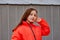 Photo of teenage girl on a grey wall background. Teenager girl in orange jacket