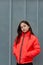 Photo of teenage girl on a grey wall background. Teenager girl in orange jacket