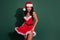 Photo of tempting lady prepare undress role-play striptease wear hat santa dress  green color background