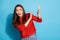 Photo of terrified lady look side empty space raise arms stopping gesture wear red sweater isolated blue color