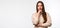 Photo of Thoughtful young woman with long chestnut hair standing with hand raised on chin. Place for ad