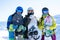 Photo of three athletes wearing helmets and snowboards in hands at snow resort.