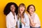 Photo of three carefree positive girls dark skin laughing look empty space isolated on yellow color background