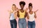 Photo of three funny cute multi-ethnic girls friends posing isolated over pink pastel studio background