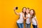 Photo of three funny ladies holding telephone taking selfies wear casual clothes isolated yellow background