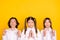 Photo of three hopeful dreamy kids crossed fingers look empty space wear white shirt isolated yellow color background