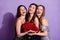 Photo of three inspired ladies hold bouquet flowers enjoy wear glossy dresses isolated purple color background