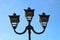 photo of three modern metal LED lamps in vintage style on a single post against a blue sky