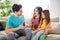 Photo of three people sit couch father tell say news mother wife small kid listen excited in house indoors