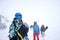 Photo of three sports people with skis and snowboard walking through winter resort
