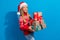 Photo of toothy beaming schoolgirl with blond hair dressed red sweater holding gift boxes on christmas isolated on blue