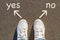 Photo on top of the sneakers and the inscription choose yes or no on the asphalt, the concept of free choice, direction of movemen