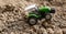 Photo of a toy green tractor on the ground in the village, agricultural machinery for cultivating the land. Picture for a toy