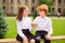 Photo of two best buddies redhead schoolkids sit bench hold little fingers wear white shirt uniform park outdoors