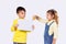 Photo of two children, boy is holding the white paper in his hands and girl tries to cut paper with scissors yellow