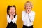 Photo of two classmate schoolkids hands cheeks toothy smile wear school uniform isolated yellow color background