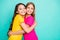 Photo of two cute amazing girls with hair long embracing each other while isolated with teal background