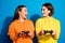 Photo of two funny ladies holding in hands joystick playing exciting video game rejoicing wear casual bright yellow