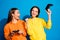 Photo of two funny two ladies holding in hands joystick playing video game rejoicing after win wear casual bright yellow