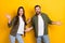 Photo of two overjoyed satisfied partners raise opened hands palms isolated on yellow color background