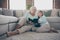 Photo of two people aged granny little granddaughter sitting floor near sofa reading together girl cute hugging grandma