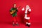 Photo of two people elf play guitar santa enjoy wear x-mas costume coat headwear isolated red color background