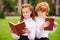 Photo of two people foxy kids sit bench hold two book curious boy peek pages read wear white shirt uniform park outside