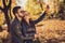 Photo of two people students girl guy hug make selfie on smartphone send air kiss in fall september park wear jacket