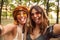 Photo of two stylish hippies women, smiling and taking selfie while walking in forest