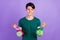 Photo of unhappy upset young man hold bottles clean housekeeper isolated on violet color background