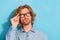 Photo of unsure suspicious young guy dressed jeans shirt arm eyewear looking empty space  blue color background