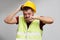 Photo of upset builder in yellow helmet in vest on empty gray background.