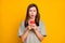 Photo of upset shocked young woman hold phone negative comment reaction isolated on yellow color background