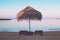 Photo of vacant beach shack made up of dried palm leaves on a deserted beach of island during sunset amidst