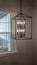 Photo Vertical Geometric chandelier hanging from the ceiling of home against window and wall