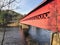 A photo of the Wakefield Covered Bridge, a red wood walking bridge over the gatineau river in Wakefield, Quebec, Canada.