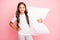 Photo of wavy cheerful hispanic brunette positive preteen embracing her soft pillow wearing white t-shirt trousers