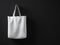 Photo white color cotton textile material bag hanging left side. Empty concrete black painted wall background. Highly