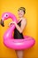 Photo of woman in black swimsuit with flamingo lifebuoy on empty orange background