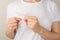 Photo of woman in white t-shirt holding pastel pink ribbon symbol of breast cancer awareness on  grey background