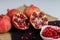 In this photo you can see a still life of several pieces of pomegranate fruit of an intense red color on a slate plate. It is a