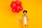 Photo of young african lady thoughtful finger touch chin party event many balloons isolated over yellow color background