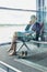 Photo of young attractive airport staff sitting while talking on smartphone