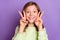 Photo of young attractive school girl happy positive smile show peace v-sign funny isolated over violet color background