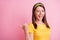 Photo of young attractive smiling happy girl wink eye pointing finger thumb in copyspace isolated on pink color