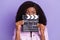 Photo of young beautiful charming african lovely woman cover close mouth with movie clapper  on violet color