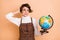 Photo of young beautiful worried anxious girl in glasses hold globe have problems in geography isolated on beige color