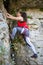 Photo of young brunette tourist climbing over rock