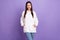 Photo of young charming positive attractive woman hold hands hoodie pockets isolated on purple color background