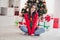 Photo of young cheerful pretty brown long hairstyle girl wear red ugly sweater sitting crossed legs wish more gifts